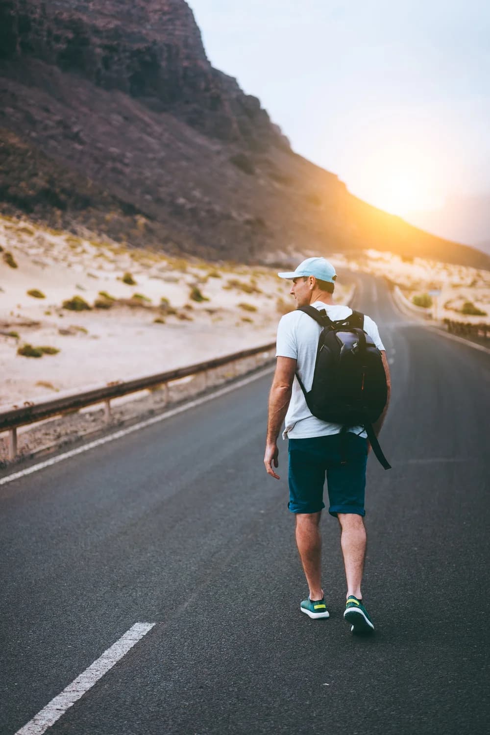 storyblocks-traveler-with-backpack-walks-in-the-center-of-an-epic-winding-road-huge-volcanic-mountains-in-the-distance-behind-him-sao-vicente-cape-verde_HWo8IkFsG.jpg